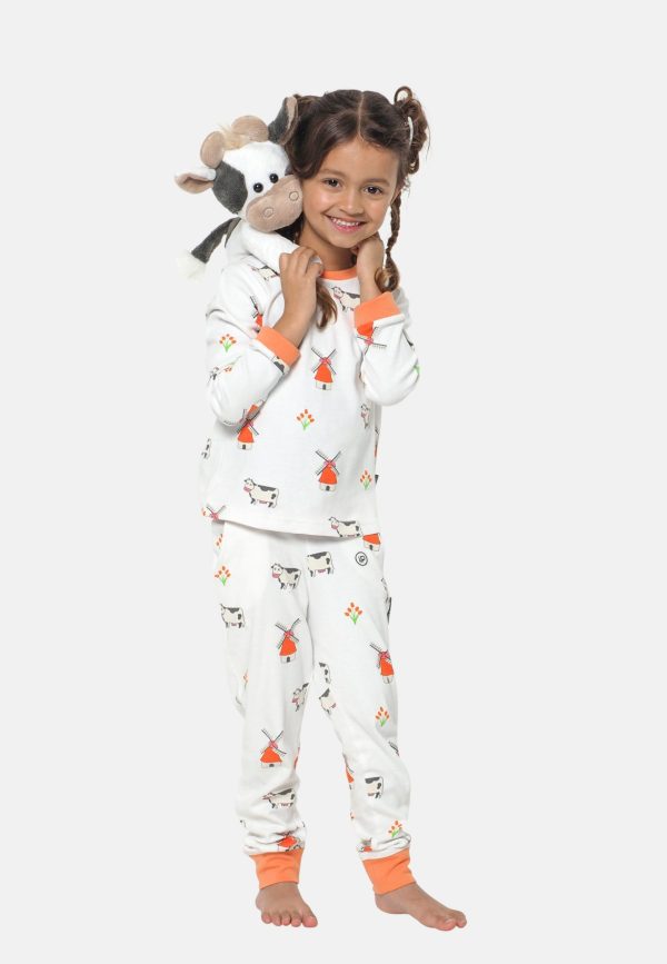 Meisje draagt een Hollandse kinderpyjama met tulpen en windmolens en houdt een koe knuffel vast