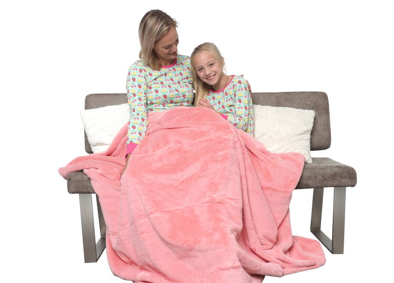 Moeder in een lichtgroene damespyjama samen met dochter in een kinderpyjama aan het zitten op een bank met een roze plait