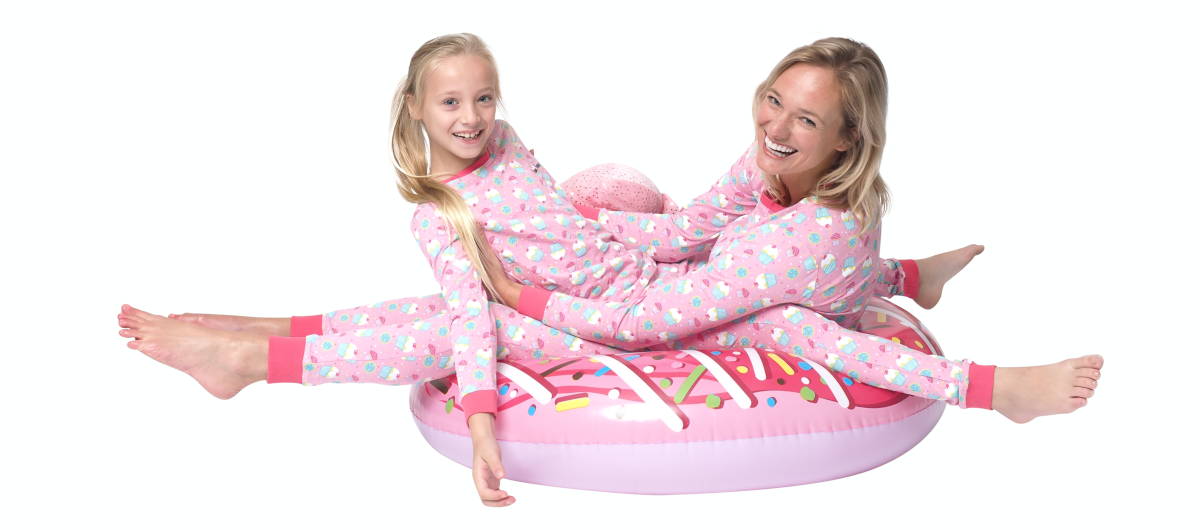 Moeder met dochter in dezelfde roze cupcake pyjama op een opblaas cupcake