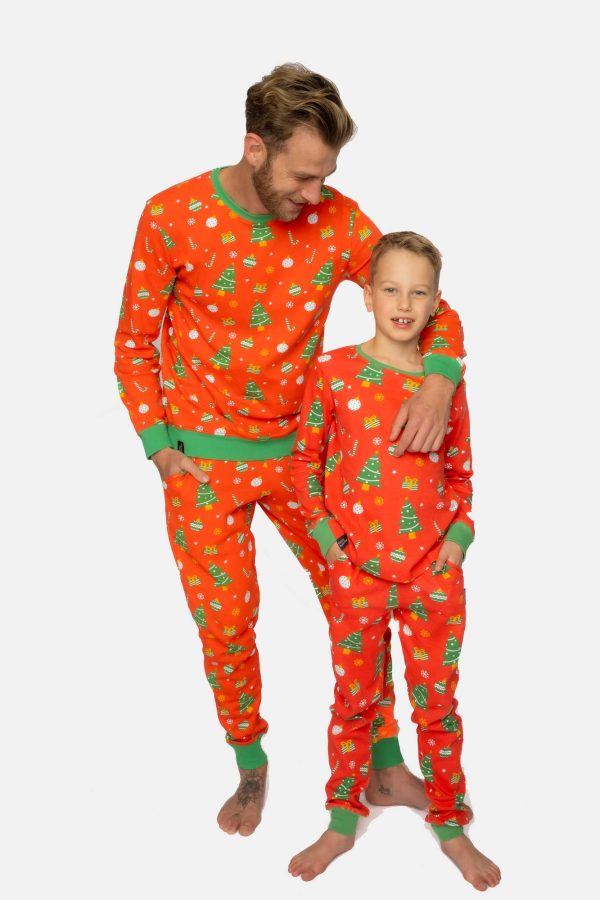 Vader en zoon in dezelfde matching kerst pyjama. Vader houdt een arm over de schouder van zijn 7 jarig zoontje.