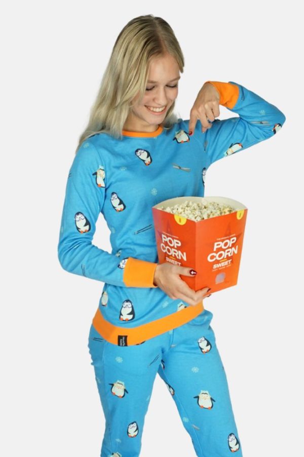 Blonde dame in een diepblauwe pinguïn pyjama. Wijst naar de popcorn in haar hand.
