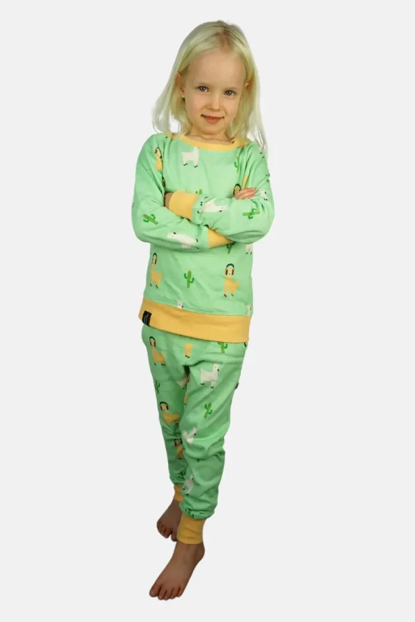 Jong kindje heeft haar armen over elkaar in een lichtgroene alpaca pyjama.