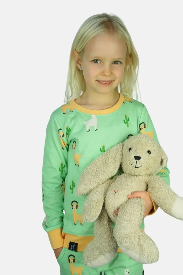 Meisje heeft een knuffel in haar arm en draag een alpaca pyjama.