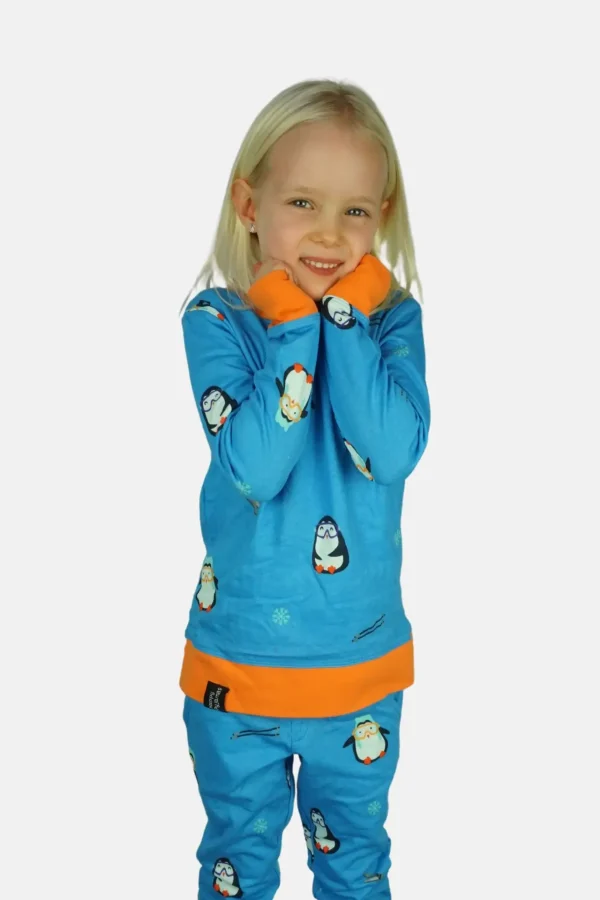 Diepblauwe kinderpyjama met oranje accenten en vrolijke pinguïns met muts en skibril.